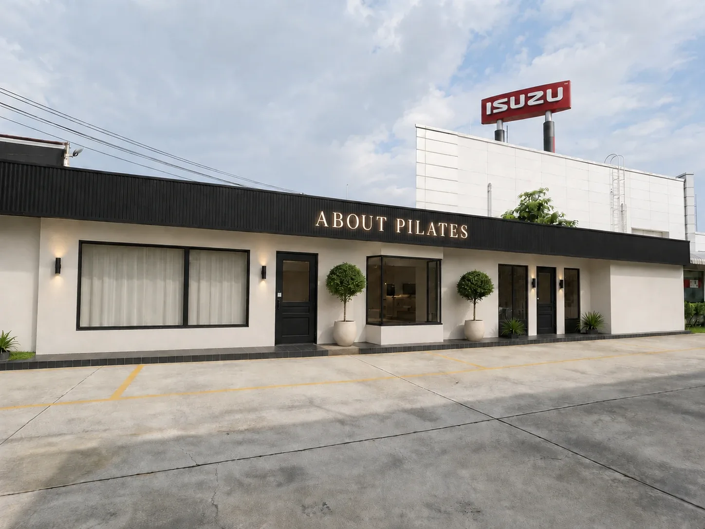 หน้าร้าน ABOUT PILATES สาขา Westville อาคารสีขาวป้ายดำ มีที่จอดรถด้านหน้า (ภาพจำลอง)